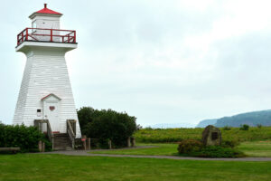 An image of the 5 Islands Lighthouse with it's stone monument and plaque on an overcast day.