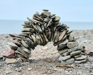 A photograph of a stone structure on a beach, with the rocks forming an archway.